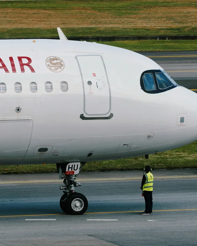 Ground crew member standing beside a commercial airplane on an airport tarmac